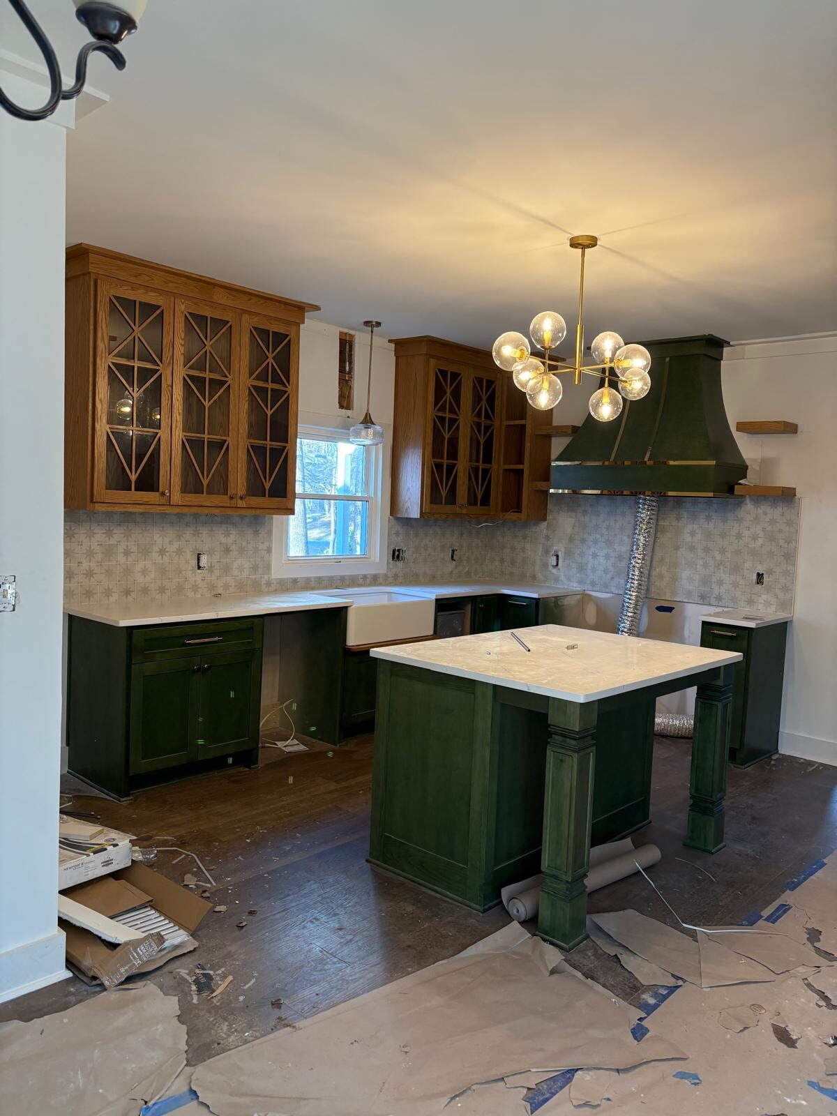 Green custom kitchen with a wood range hood and island